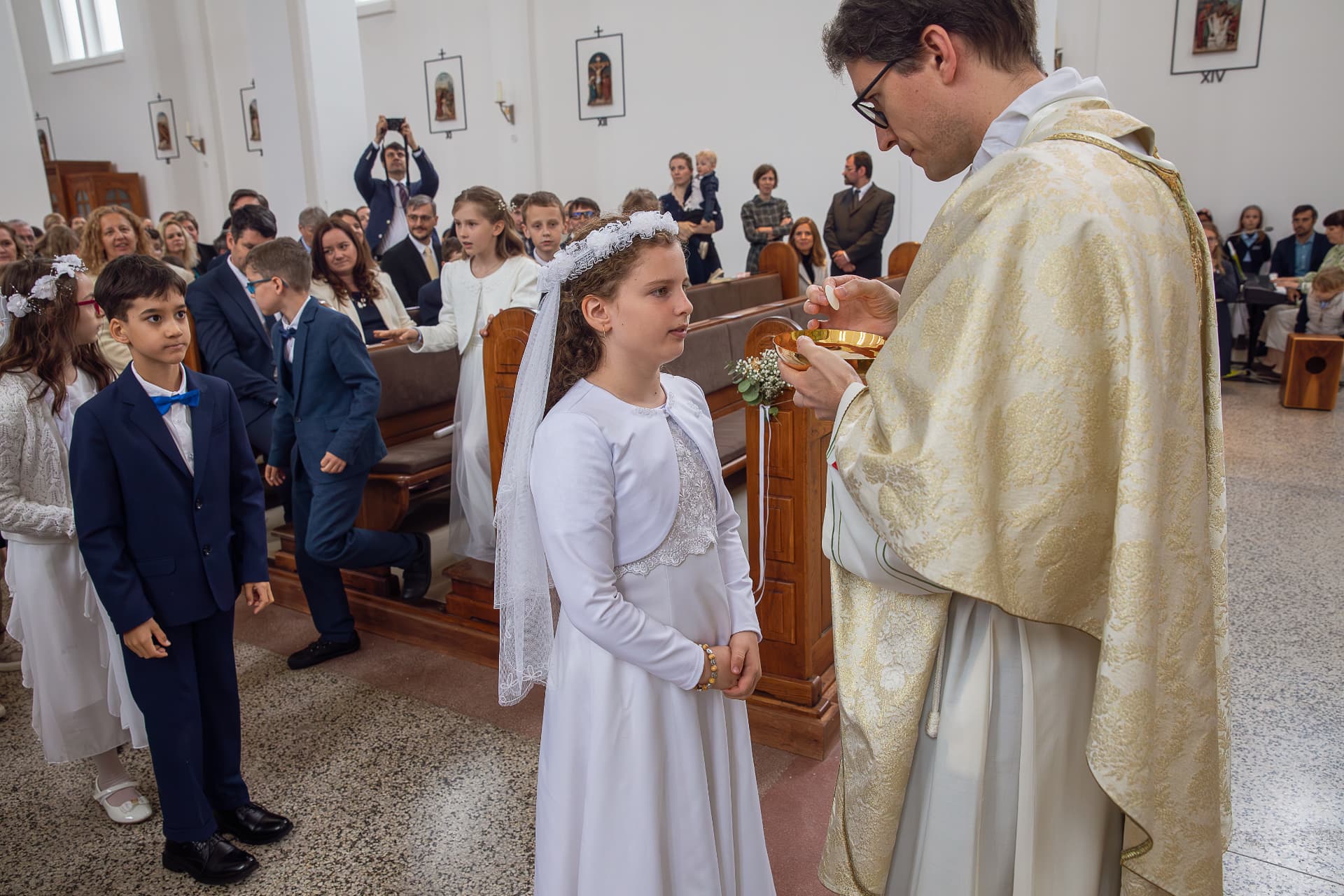 Dievča prijíma Eucharistiu z rúk kňaza